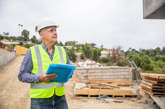 Construction worker man wearing a hard hat and holding a clipboard on a job site