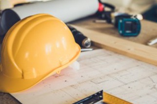 Hard hat sitting on a table next to construction blueprints and tools