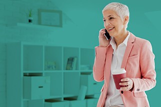 Safety professional woman with short gray hair talking on the phone in front of a teal background