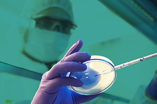 Industrial hygienist in a lab in front of a teal background