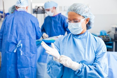 Female surgeon putting on surgical gloves before operation