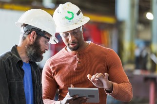 Two construction safety professional men talking and looking at a tablet computer