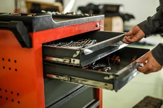 Hands reaching inside a toolbox drawer in an auto shop