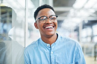 Young man with glasses smiling and considering becoming a safety professional