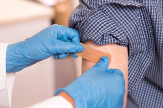 Doctor placing bandage on patients arm