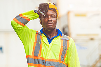 Tired dock worker wiping sweat from forehead