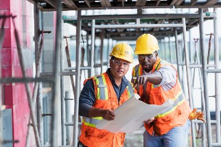 Hispanic safety professional speaking with a worker on a job site