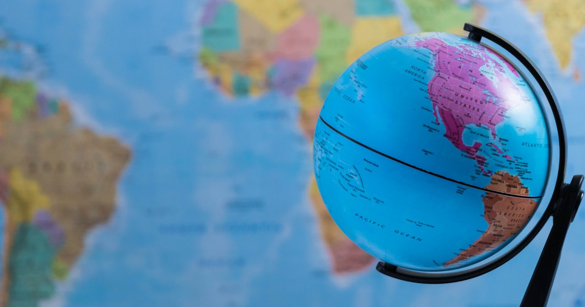 Small globe on a table in front of a world map