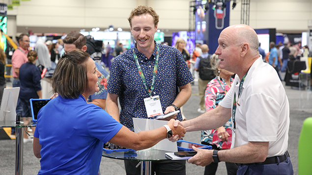 photo of a woman and two men shaking hands and smiling at an ASSP event