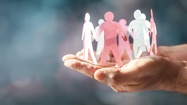 Image of outstretched hands holding paper cutout of people holding hands